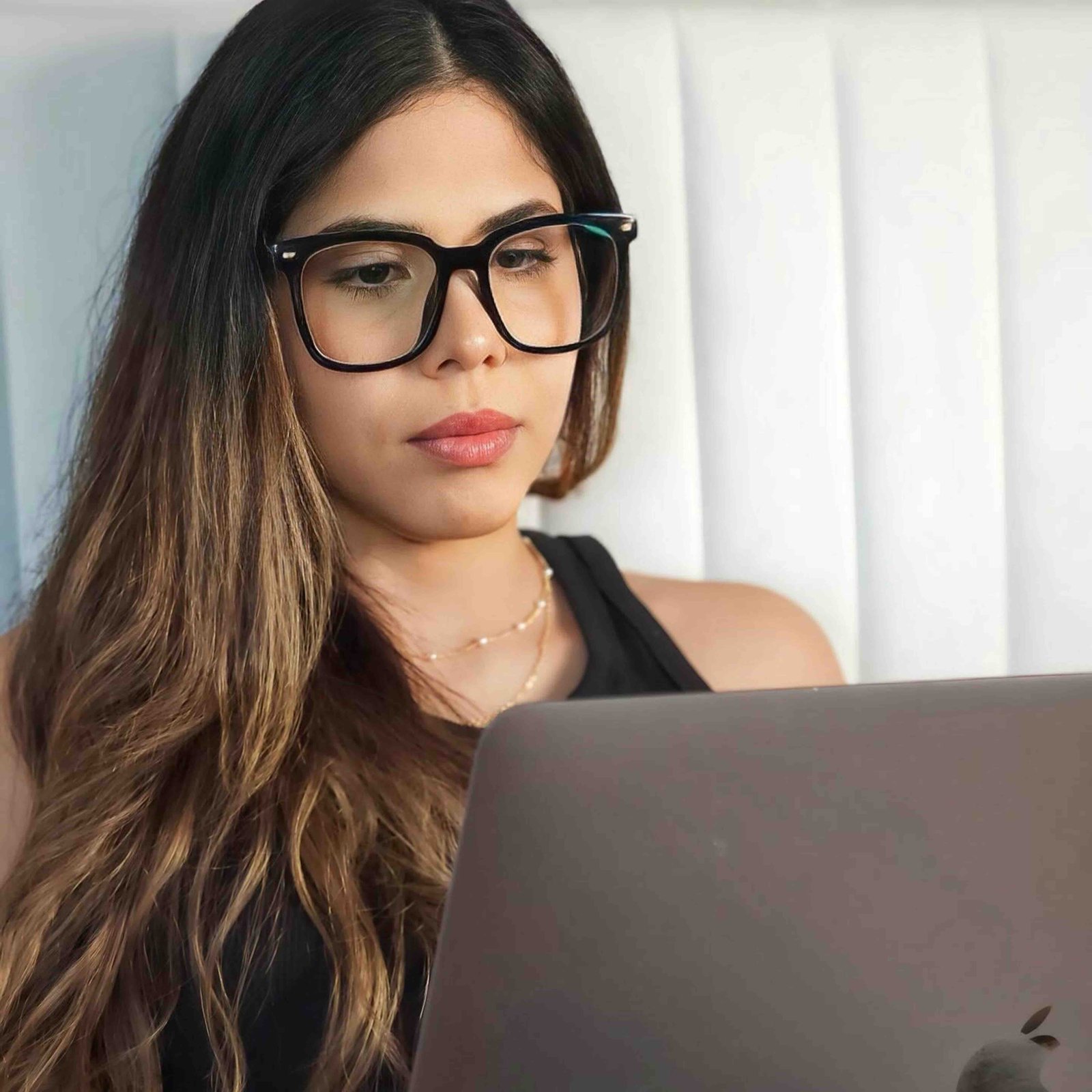 A woman wearing glasses looking at a laptop